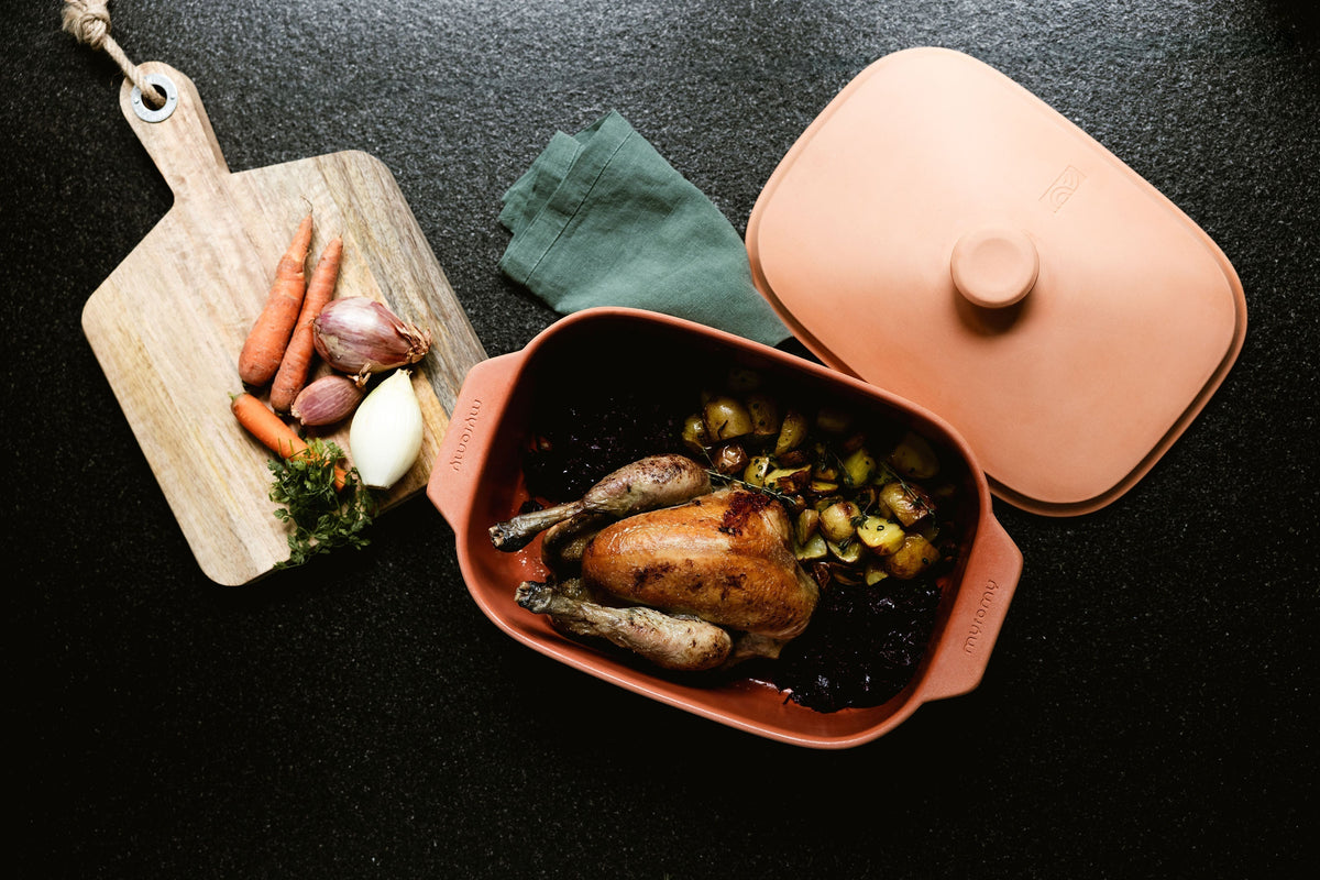 Gebratenes Hähnchen mit Gemüse im myromy Keramikbräter als Schmortopf für den Backofen, daneben der passende Keramikdeckel