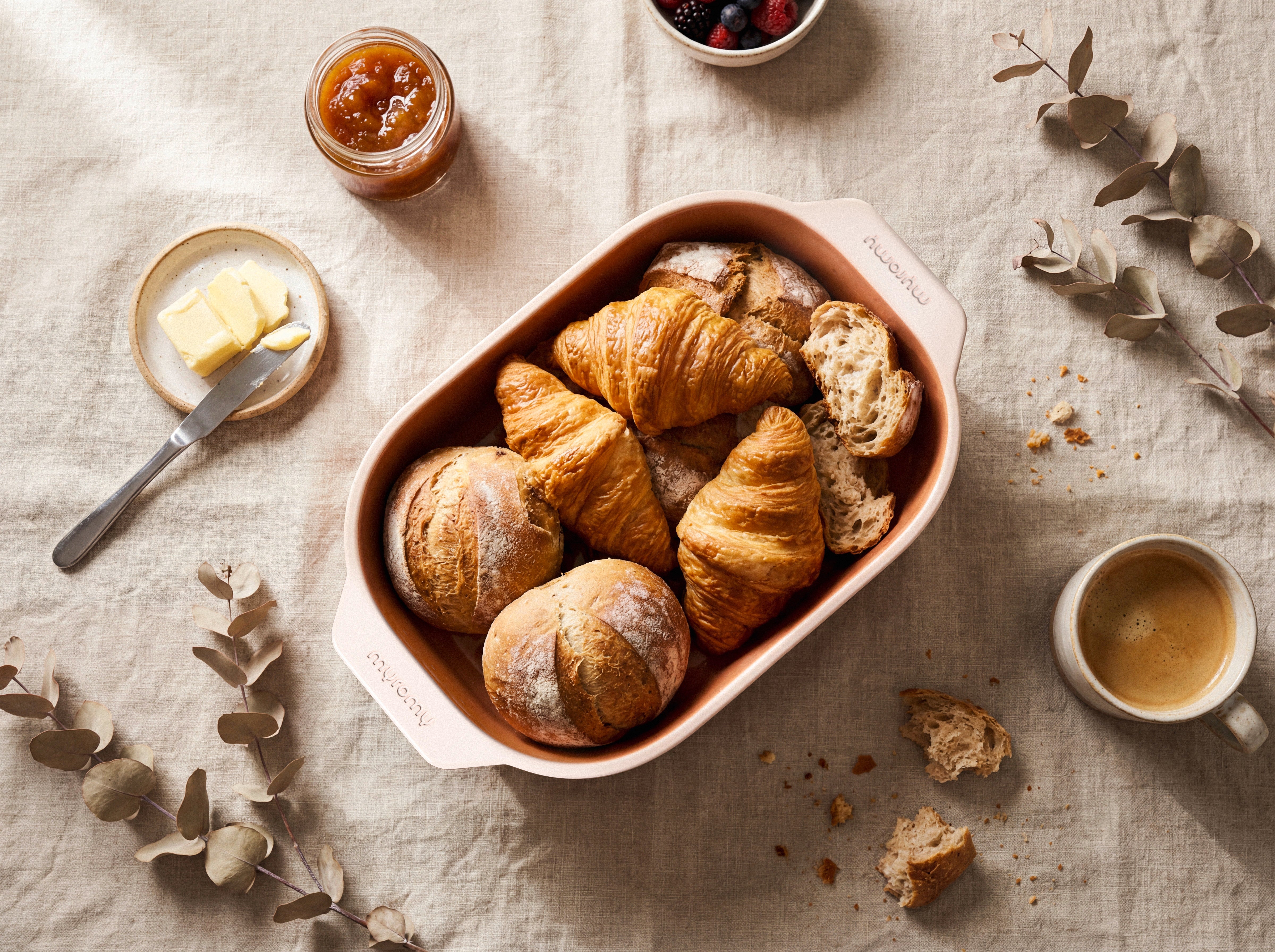 Brötchen, Croissants und Brotscheiben im myromy Brot-Frische-Topf in der Coffee Cream Edition, umgeben von Butter, Marmelade und Kaffee
