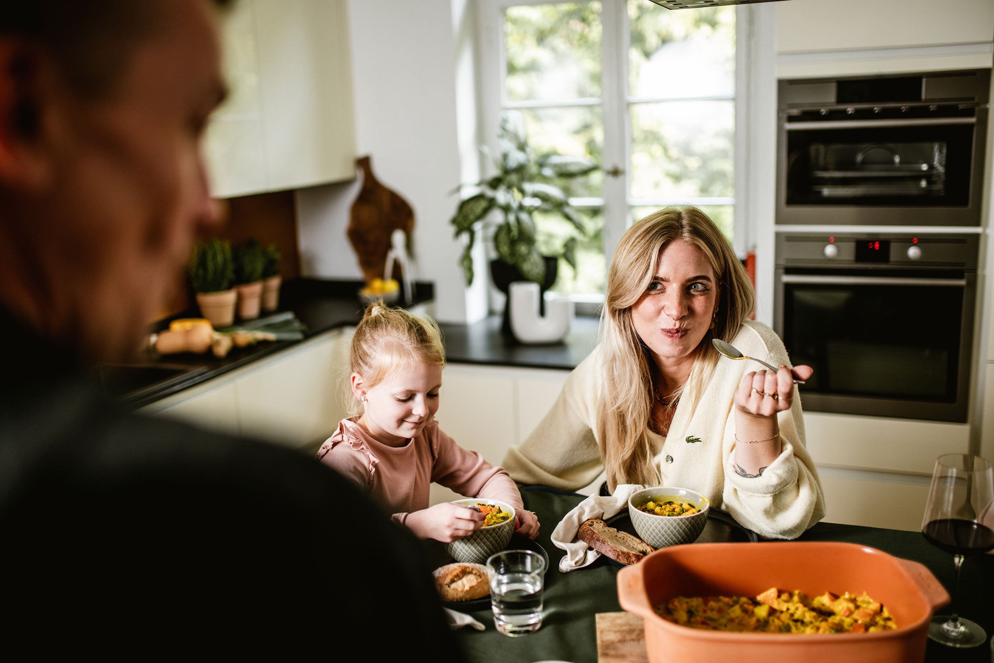 Familie beim gemeinsamen Essen mit einem myromy Keramik-Bräter als Schmortopf aus Keramik und frisch zubereitetem Gericht auf dem Tisch
