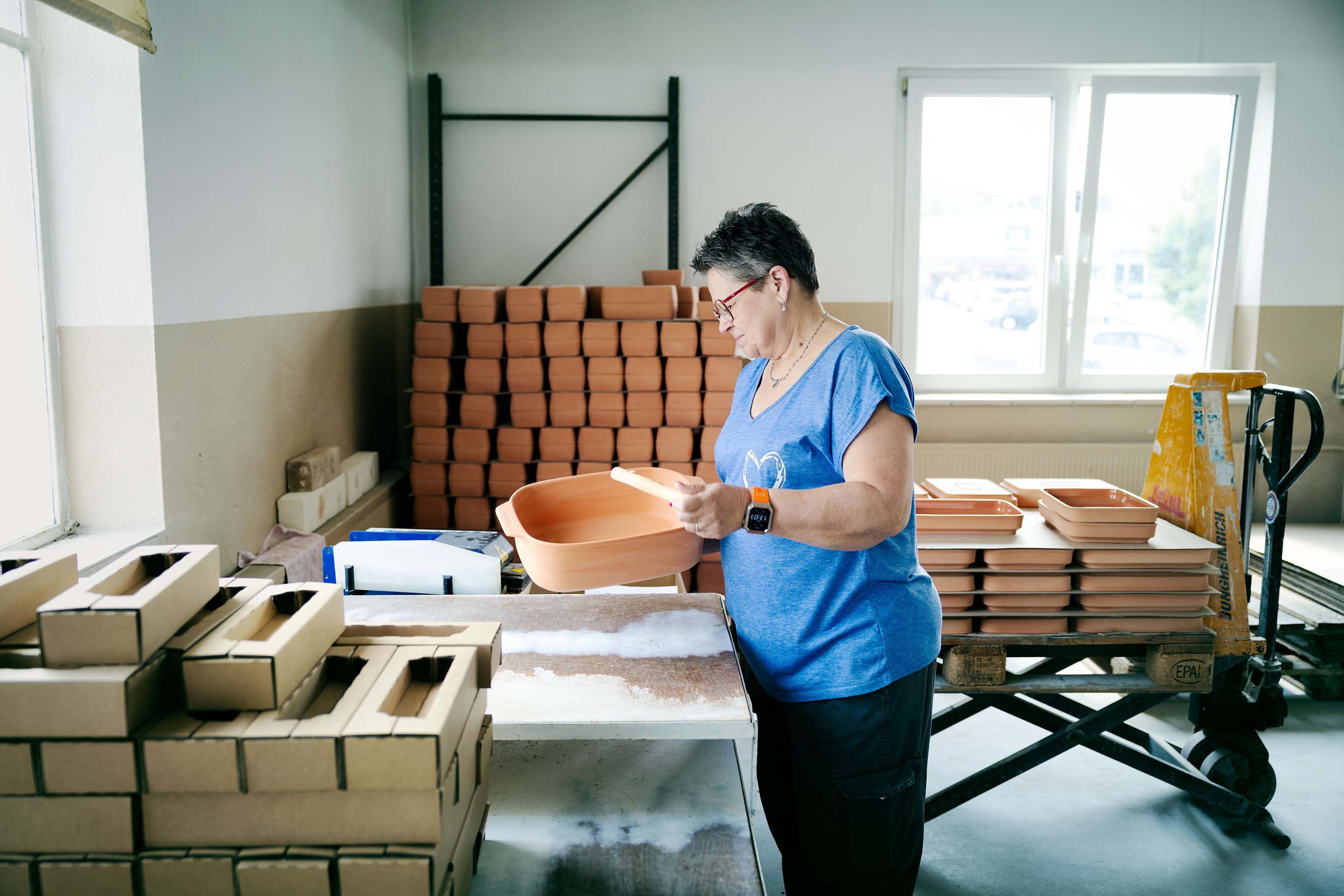 Mitarbeiterin beim Klangtest eines myromy Keramik-Bräters als Schmortopf aus Keramik zur Qualitätskontrolle in der Produktion