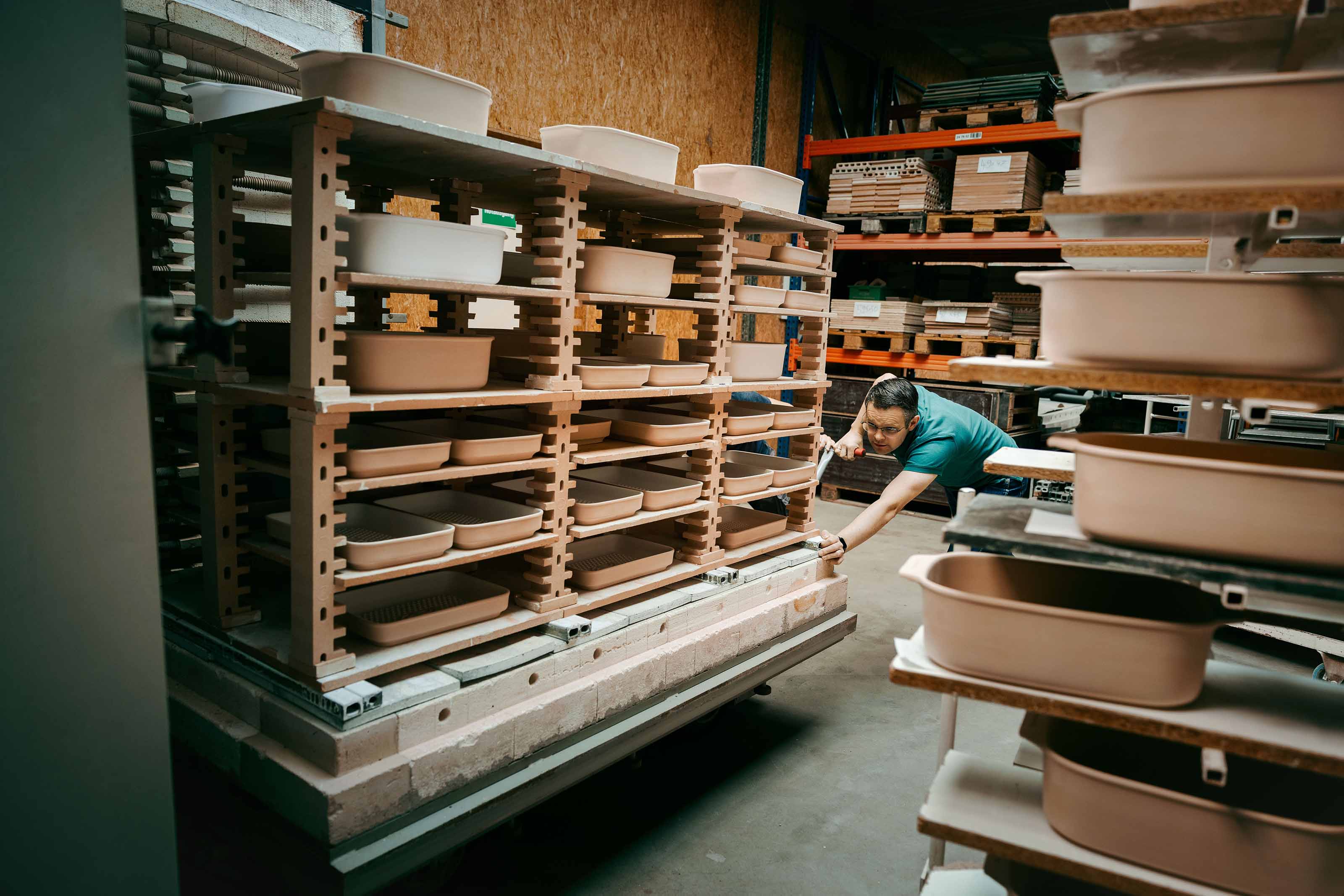Mitarbeiter in der myromy Keramikproduktion mit mehreren Keramik-Brätern und Keramikformen in der Manufaktur in Deutschland