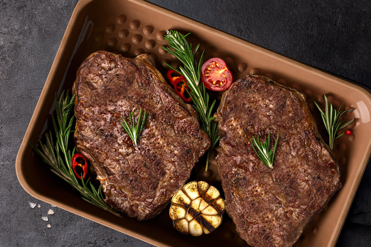 Plancha und Grillplatte aus Keramik - verwendet als Grillschale zum Garten auf dem Gasgrill sowie im offenen Feuer und der Glut – hier mit köstlichen Steaks gefüllt