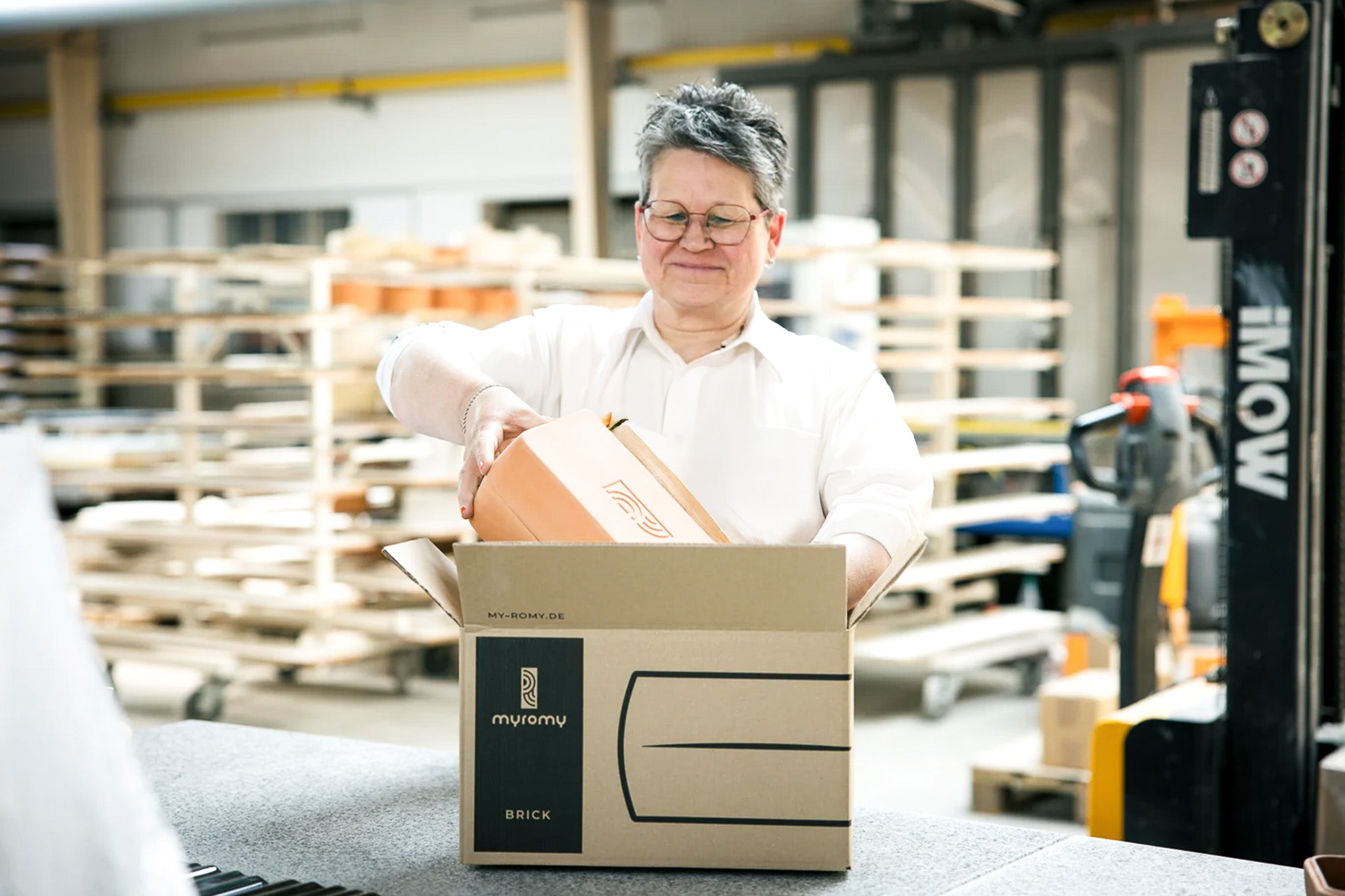 Mitarbeiterin verpackt einen myromy Keramik-Brick Backstein von Hand für den Versand in der Manufaktur in Deutschland